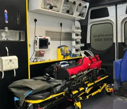 Treatment bay of a Medlink ambulance with a loaded stretcher and wall-mounted equipment