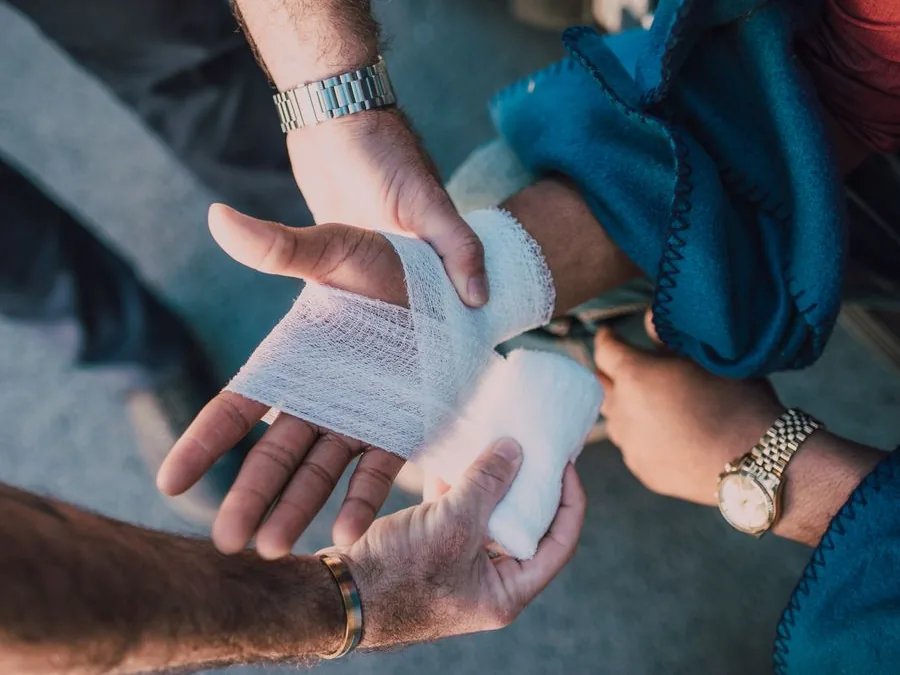 A first-aid responder applying a conforming bandage to an injured hand