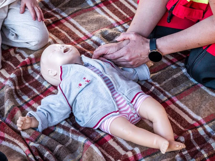 Instructor practising infant CPR on a baby training manikin